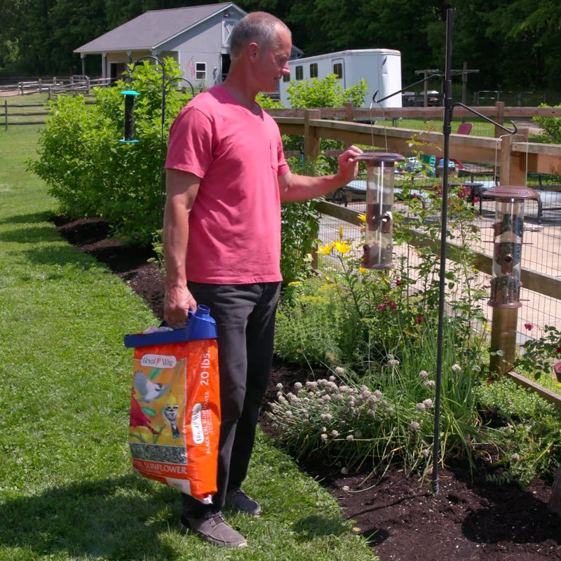 Load image into Gallery viewer, handle-it bag clip on bird seed bag being carried to bird feeder
