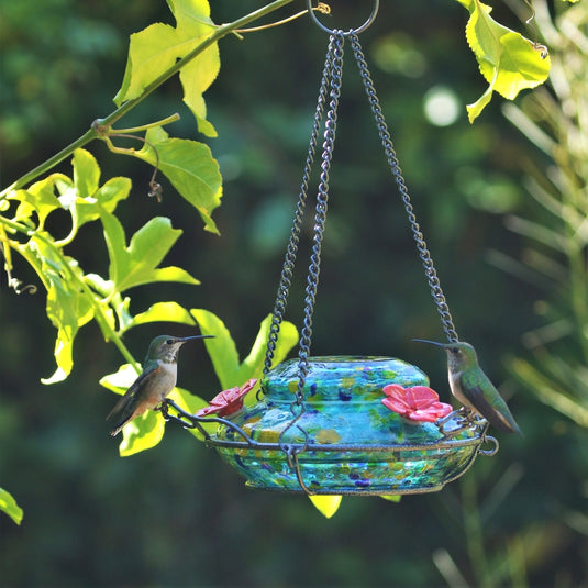 Two hummingbirds feeding from the Nature's Way Illuminated Hummingbird hand blown glass Feeder 