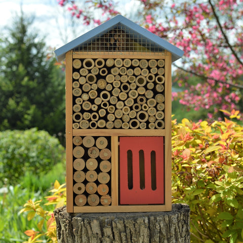 Better Gardens Multi-Chamber Beneficial Insect House sitting on stump in garden